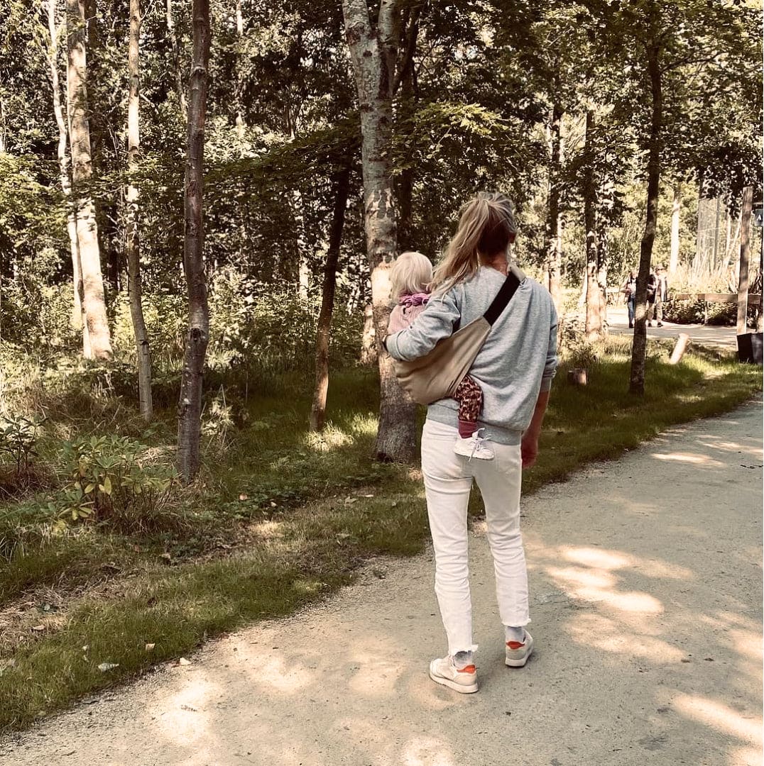 Madre disfrutando de la naturaleza con su bebé en el portabebés NAREVI, resaltando comodidad y conexión